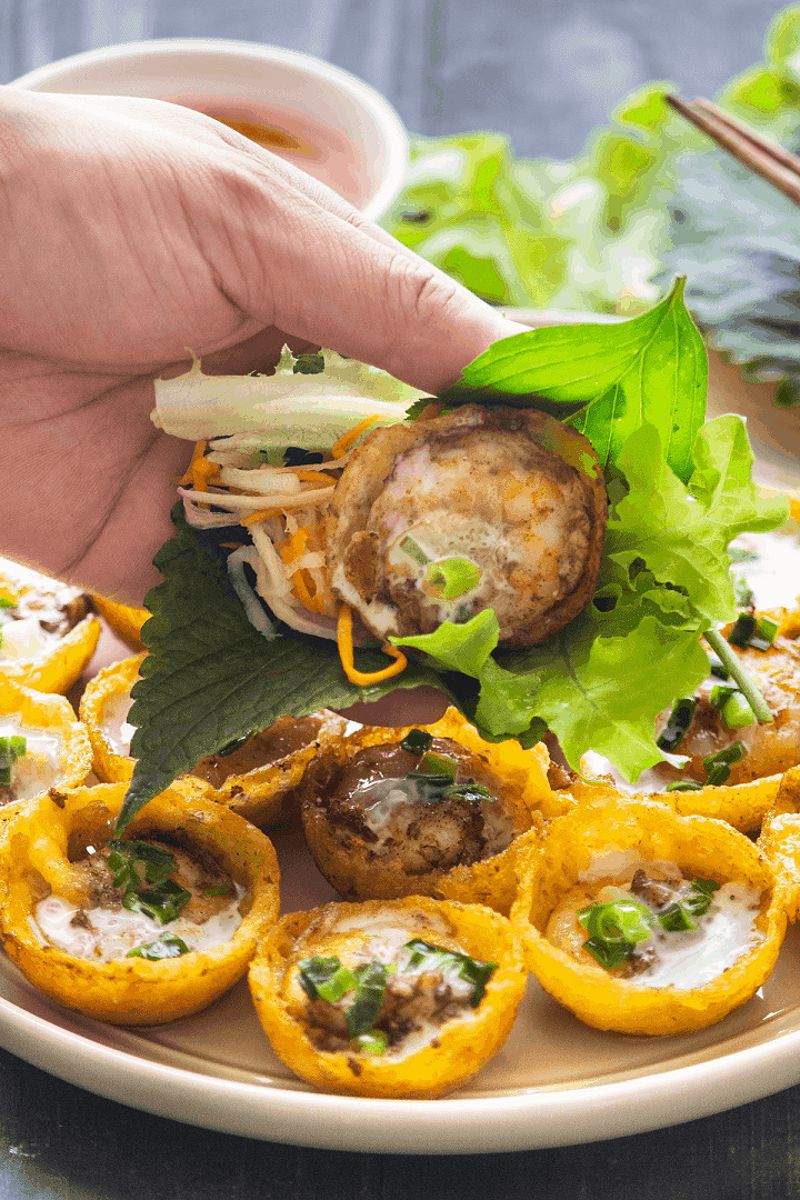 Banh khot served with fresh herbs and greens