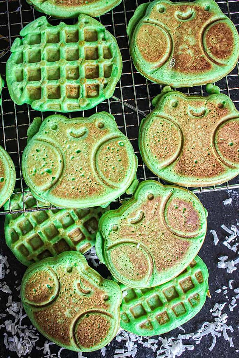 A birds eye view of frog shaped coconut pandan waffles on a wire rack