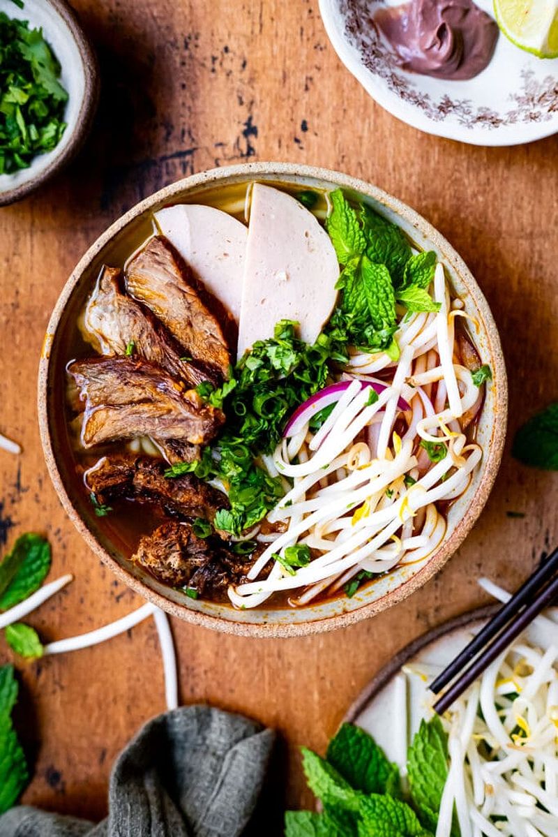 A bowl of Bun Bo Hue with fresh toppings