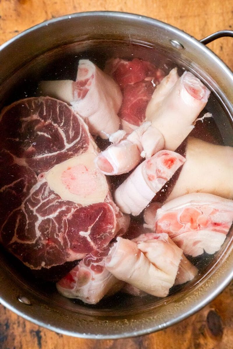 Beef shank and pork hocks in water for broth preparation