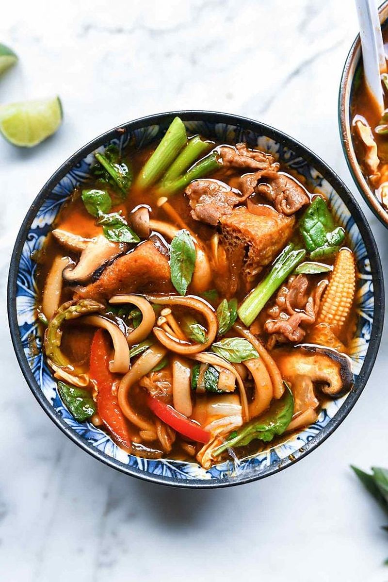 Bowl of red curry Asian hot pot with various vegetables and sliced beef