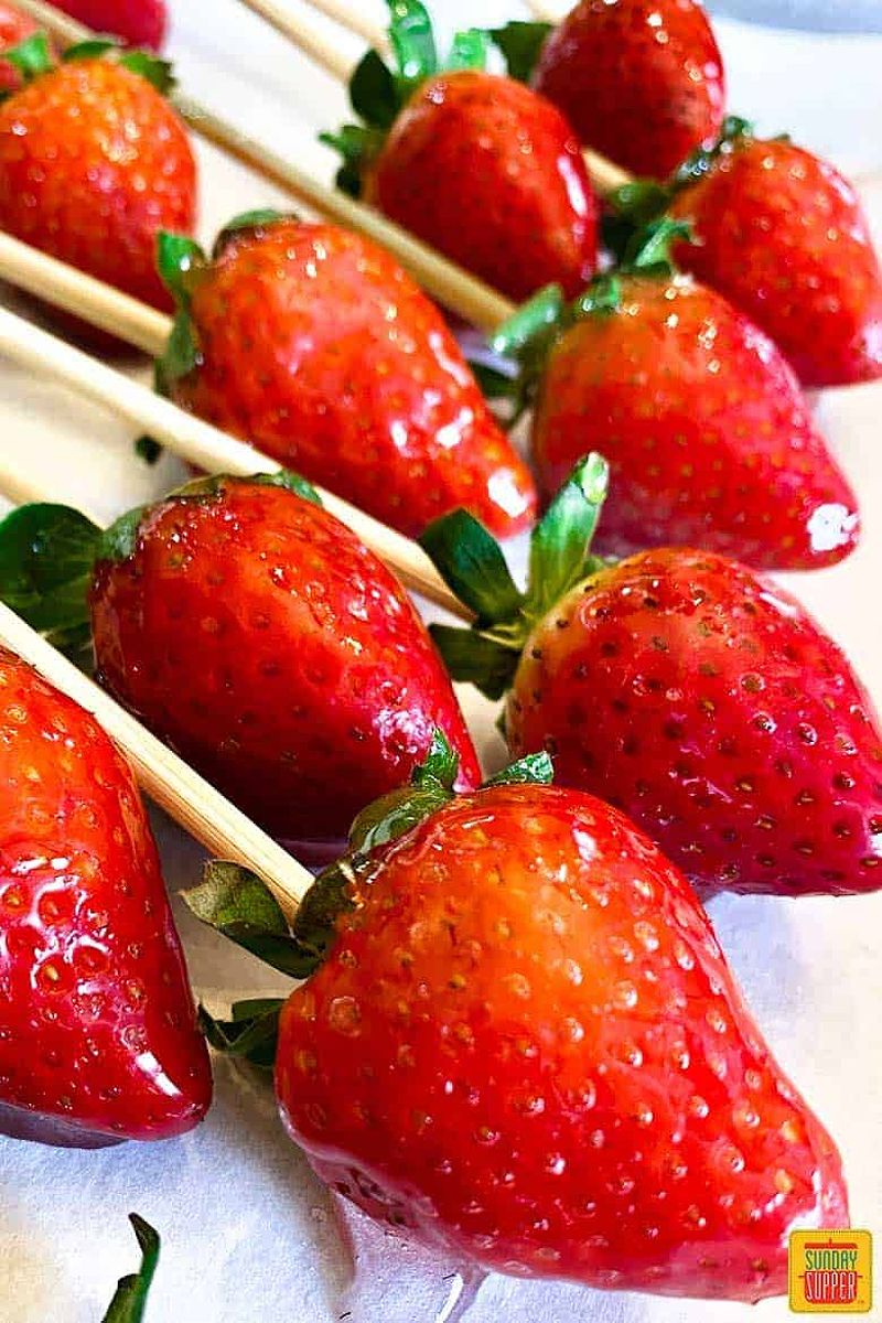 Candied strawberries on skewers over parchment paper