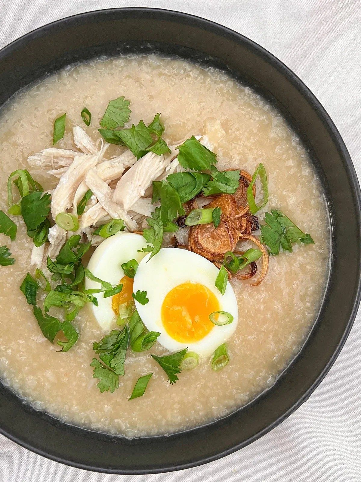 Cháo gà with toppings including egg, fried shallots, and herbs