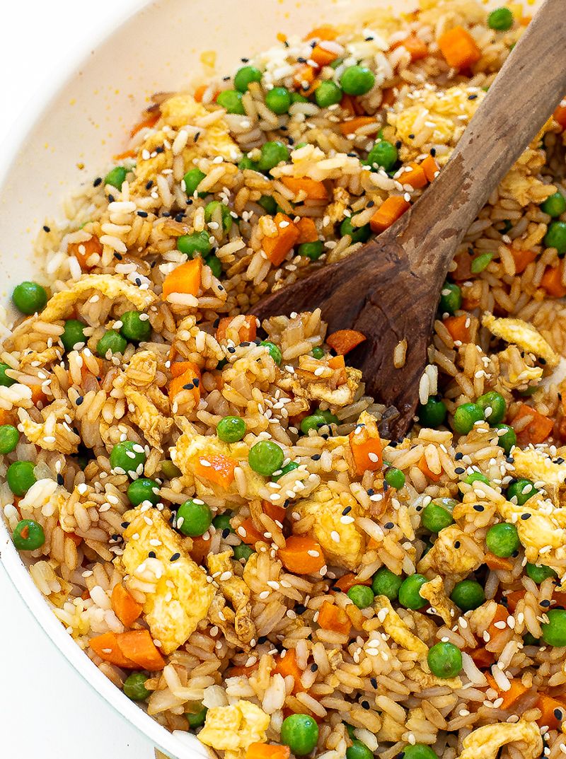 Fried rice with wooden spoon in a large skillet