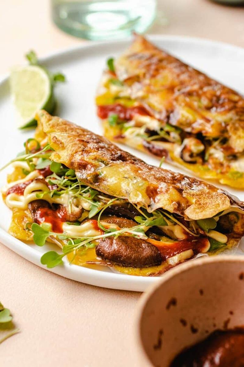 Photo shows folding the vietnamese pizza in half before serving on a white plate