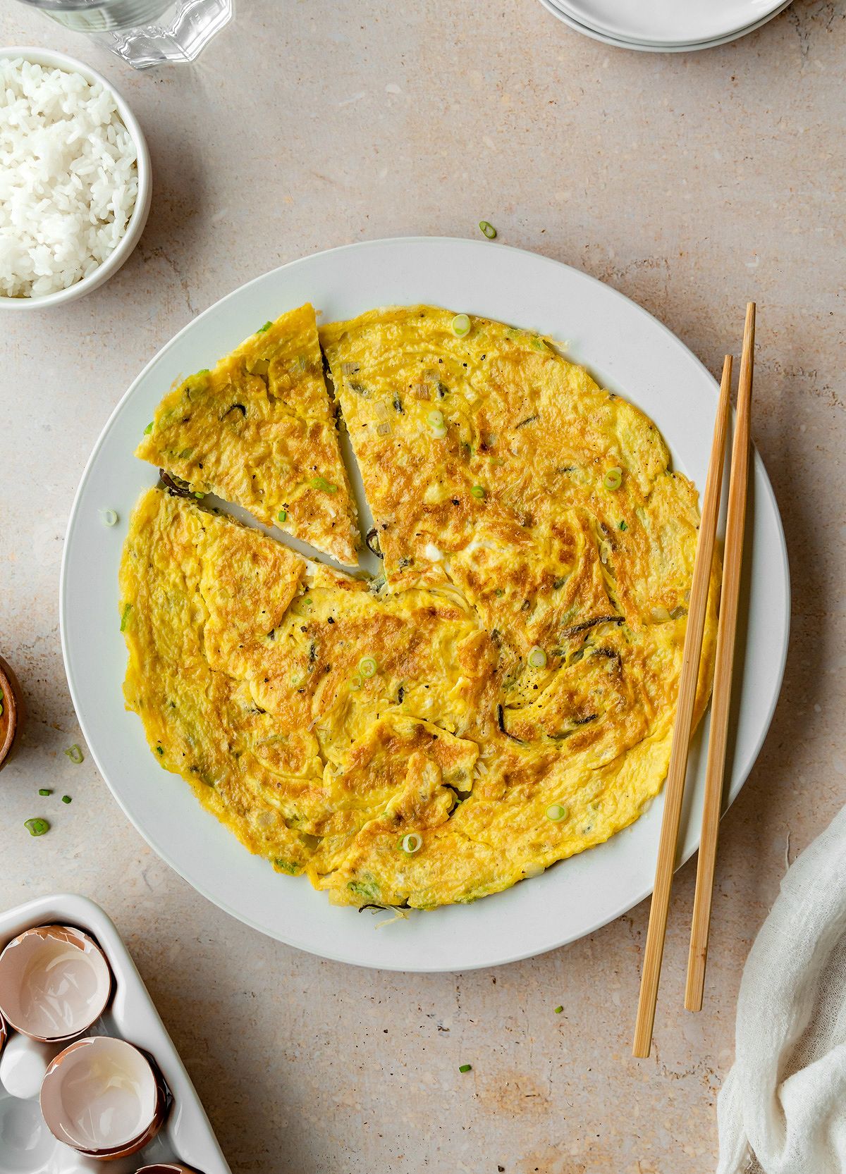 Plate of Vietnamese egg omelet with a bowl of rice and chopsticks