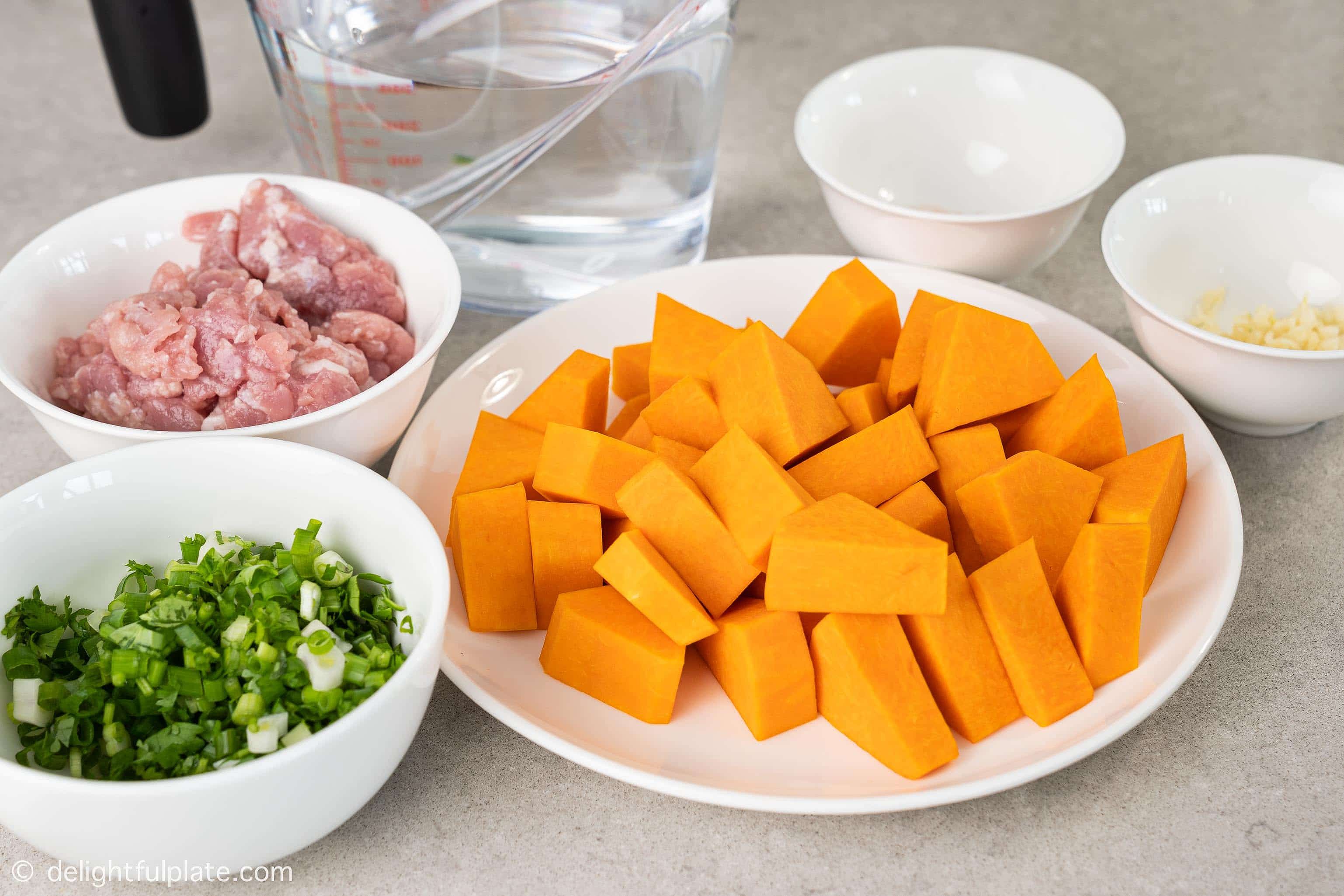 Plates and bowls containing ingredients for Vietnamese squash soup