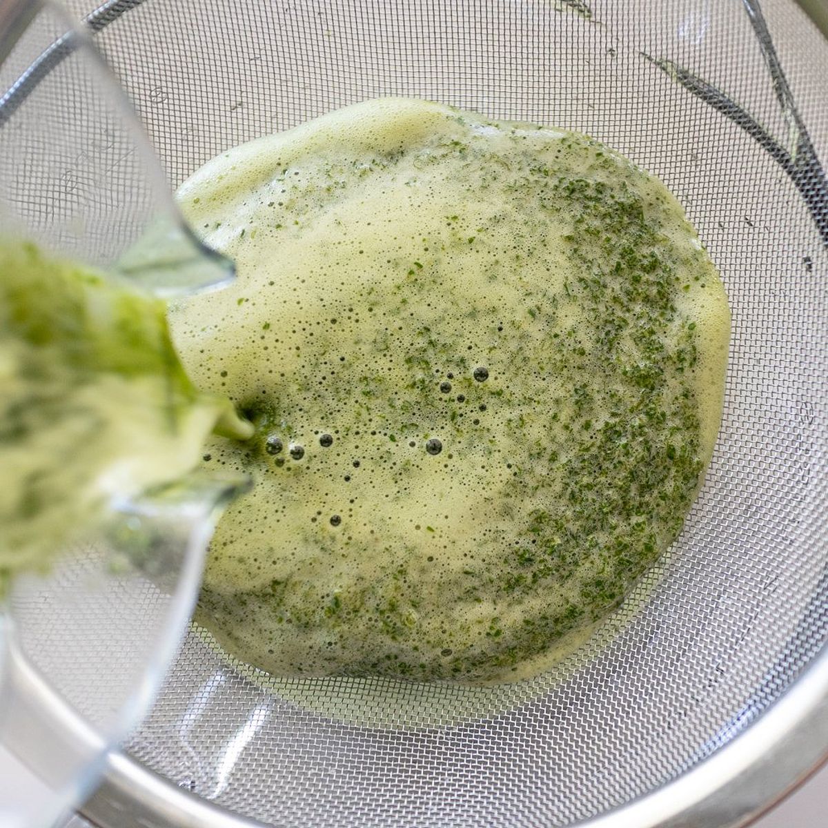 Straining Pennywort juice through a sieve for Vietnamese Pennywort Drink