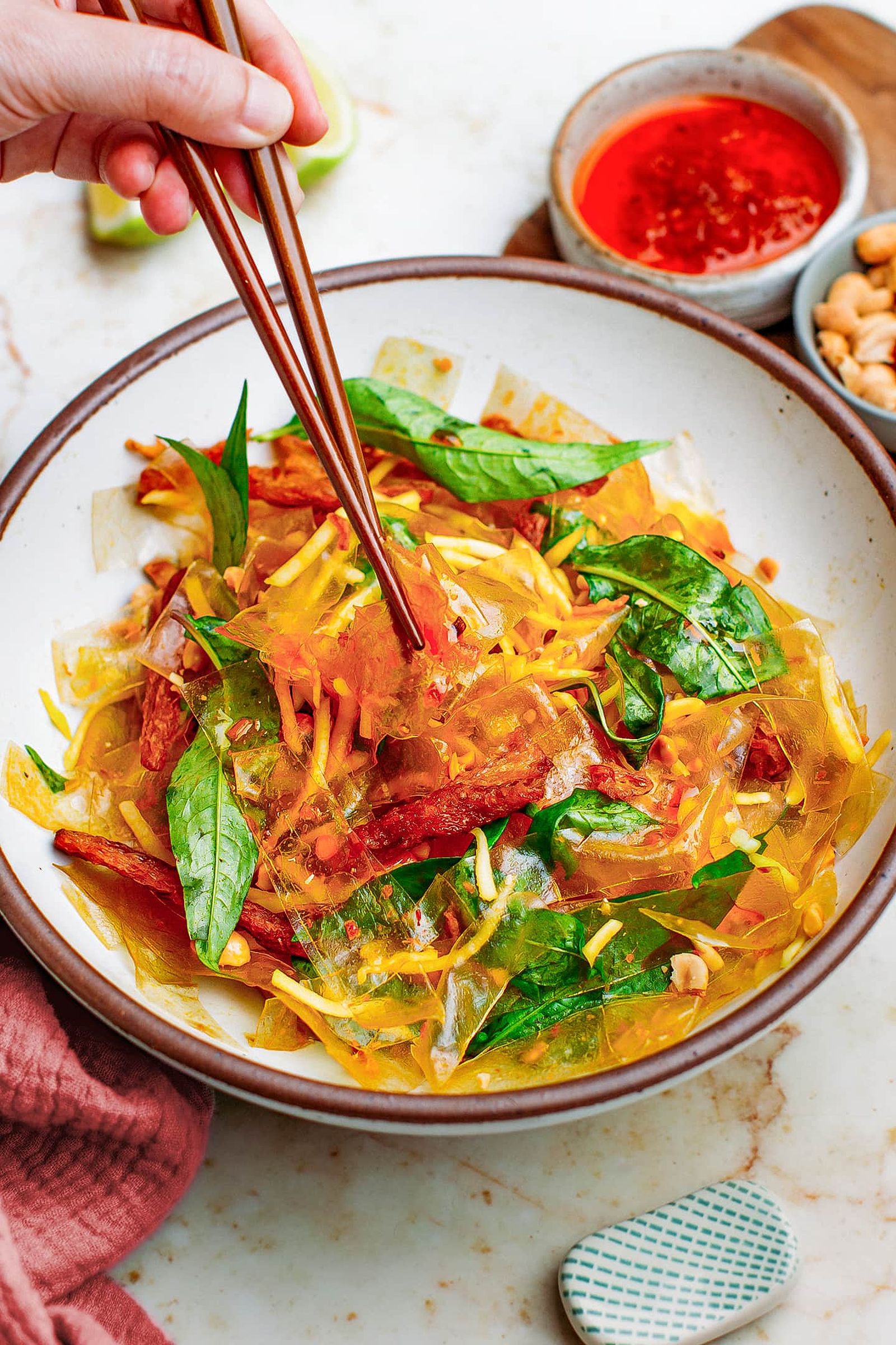 Vegan banh trang tron with rice paper and green mango in a bowl.